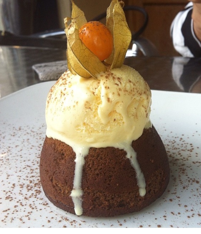 chocolate molten cake topped with ice cream and a gooseberry