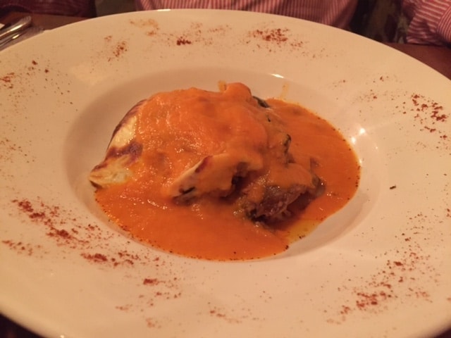moussaka with an orange sauce in a white bowl