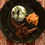 arial view of chops, rice and vegetables on black plate