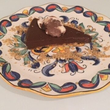 .Slice of chocolate pie with ice cream on a painted plate.