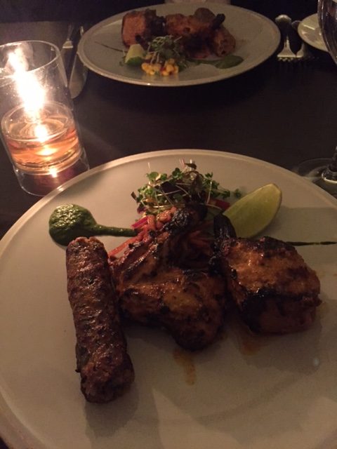 one seekh kebab and tandoori chicken on a plate by candlelight