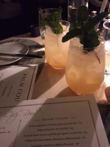Two yellow drinks on table next to menus