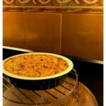 gratin in round dish cooling on a wooden tray