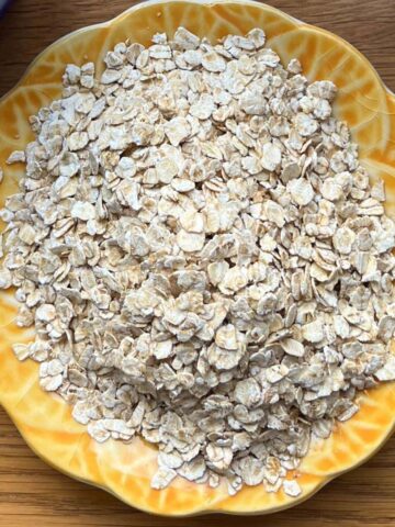 Uncooked rolled oats on small yellow plate.