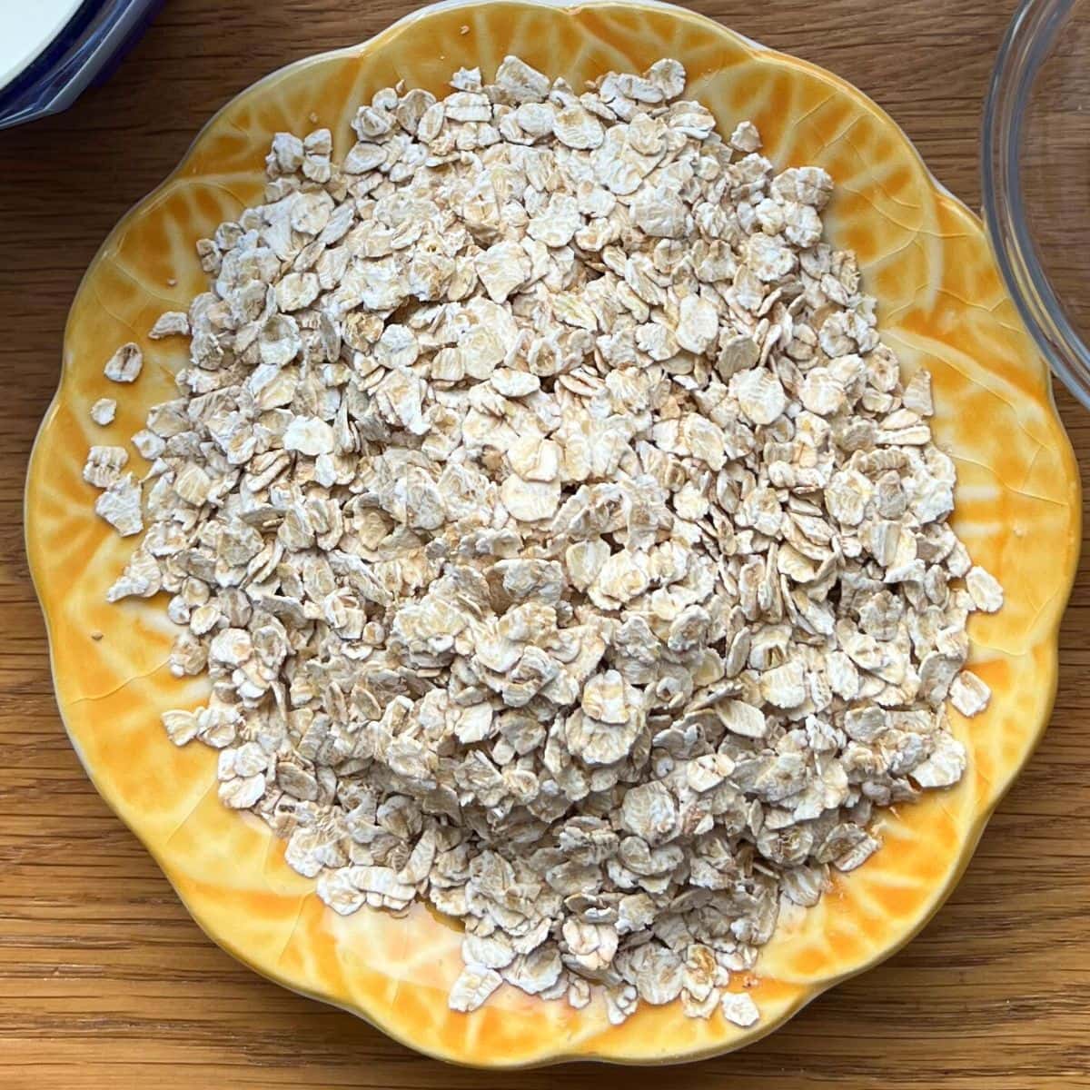 Uncooked oats on small yellow plate.