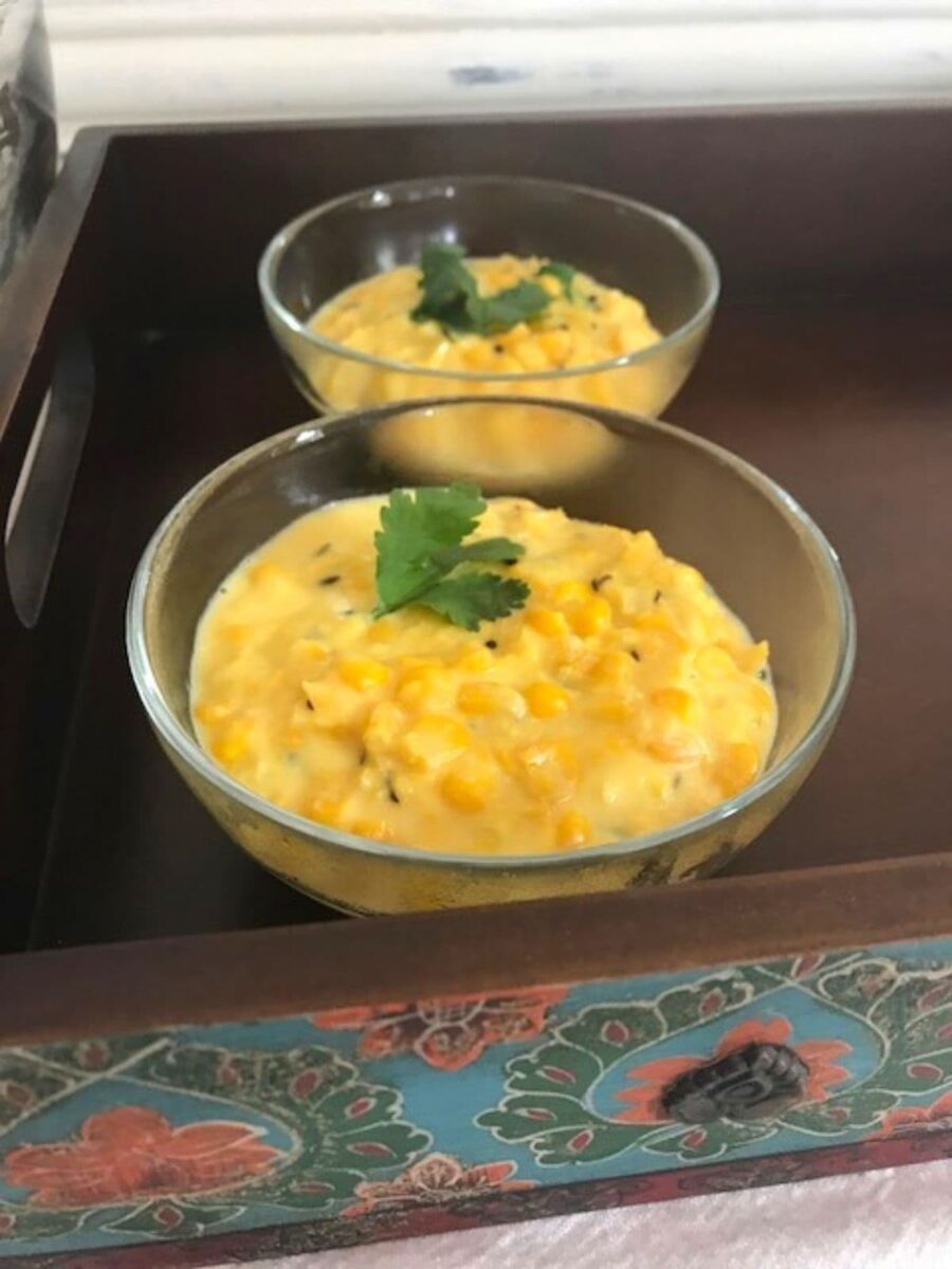 two bowls of corn on wooden tray