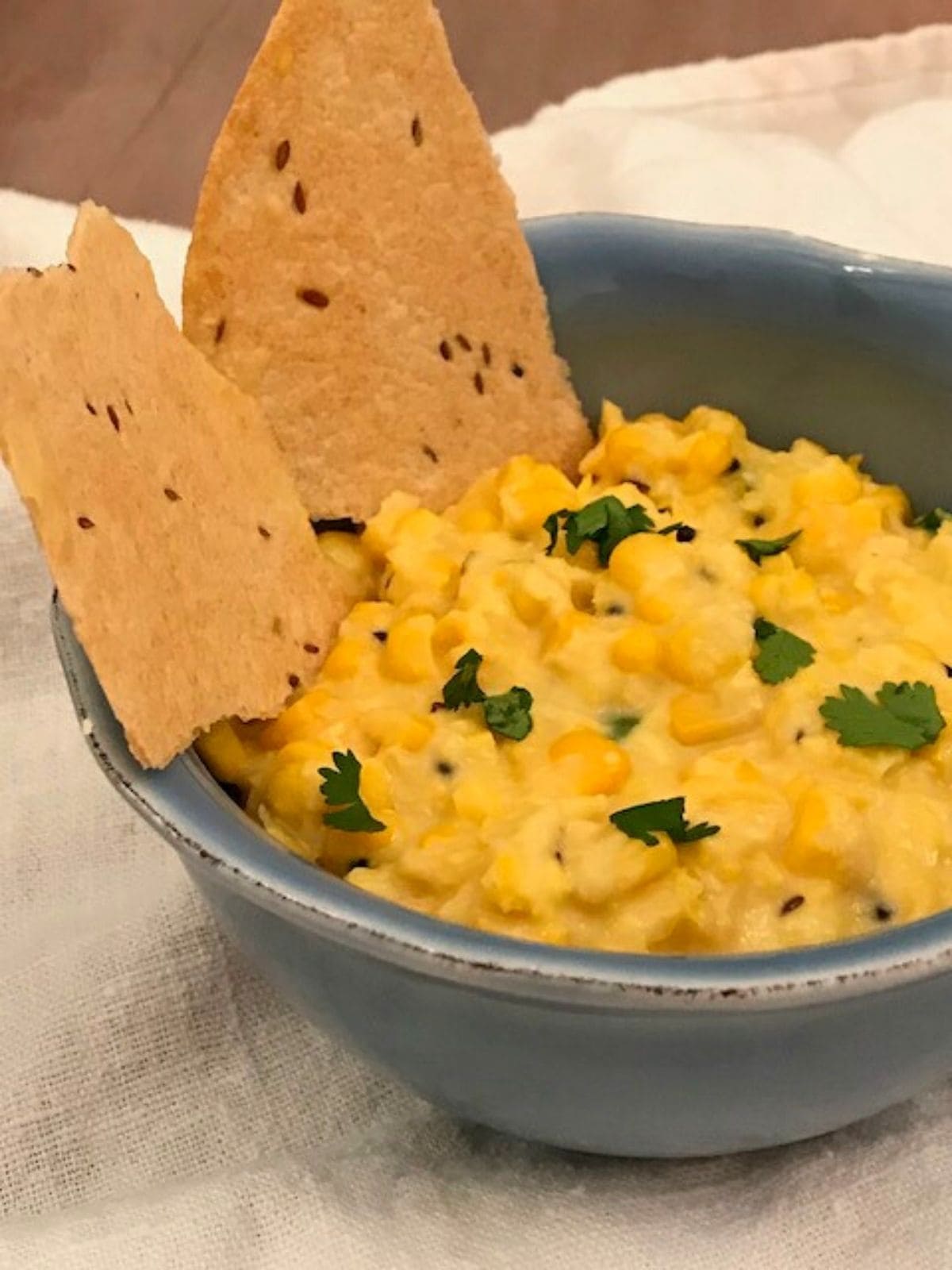 corn dip in a blue bowl with indian crispbread