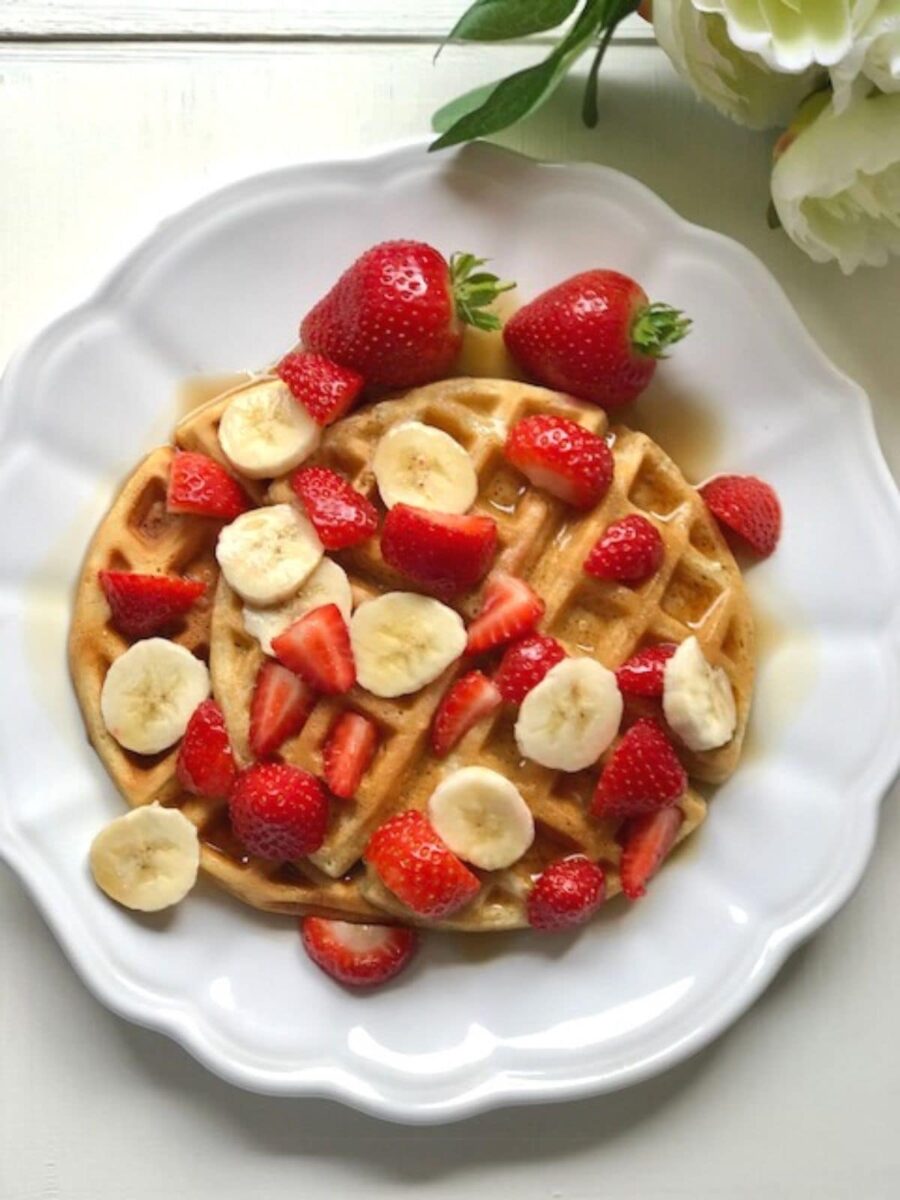 Fluffy waffles covered in sliced banana and strawberries