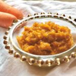 halwa in decorative glass bowl alongside 2 carrots