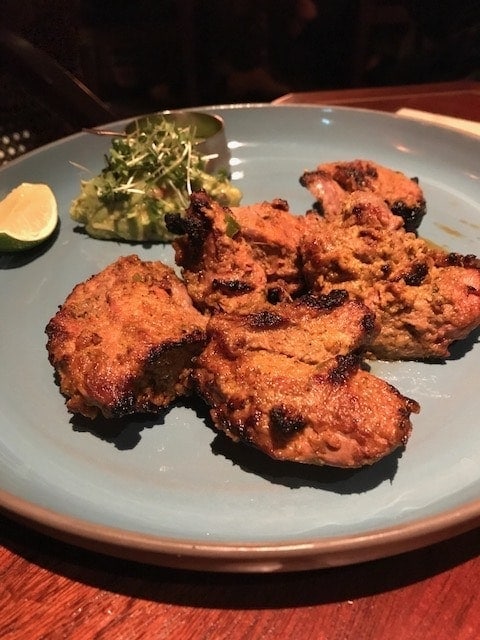 Pieces of Boti Kebab on a plate alongside a mashed avocado and watercress garnish