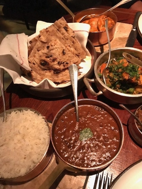 Rice, dal, parathas, vegetables in serving bowls on table