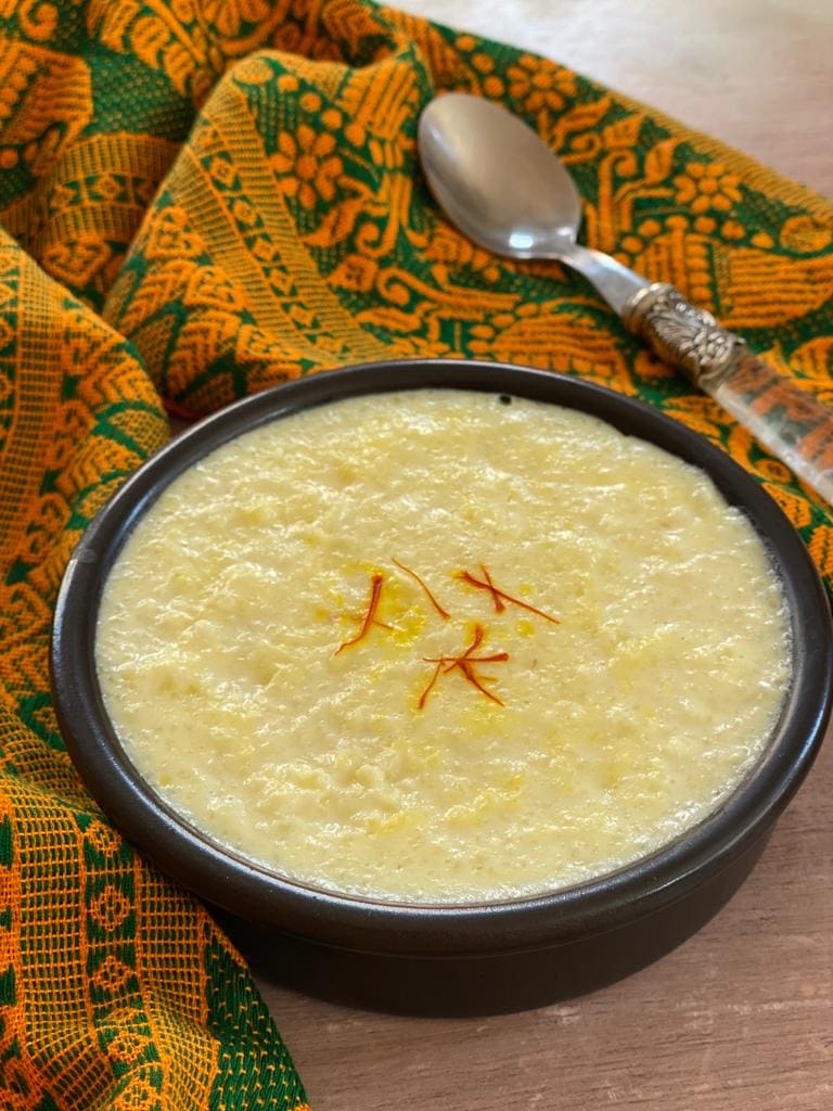 Kheer in a black bowl garnished with saffron.