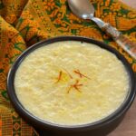 kheer in small black bowl with saffron strands.