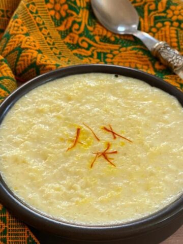 kheer in small black bowl with saffron strands.