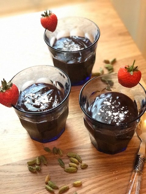Chocolate and cardamom pudding in small glasses with strawberries