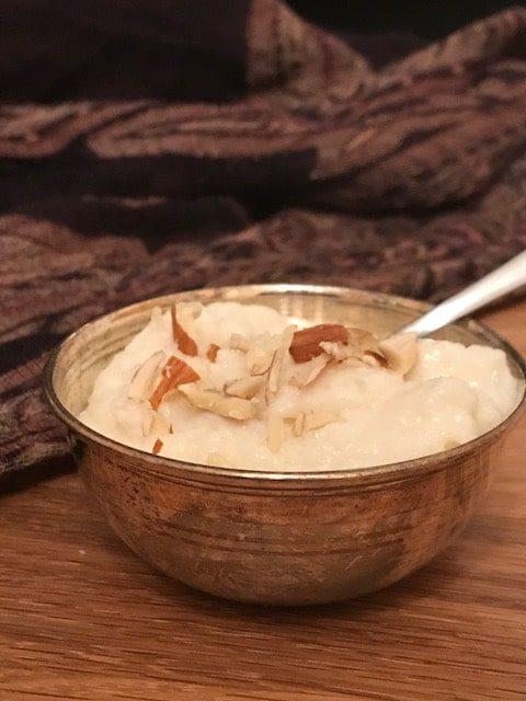Kheer in a small silver bowl garnished with crushed almonds