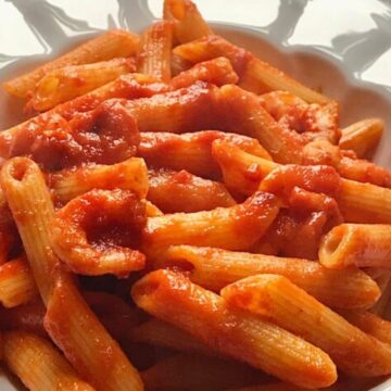 Pasta with shrimps in tomato sauce in a white bowl.