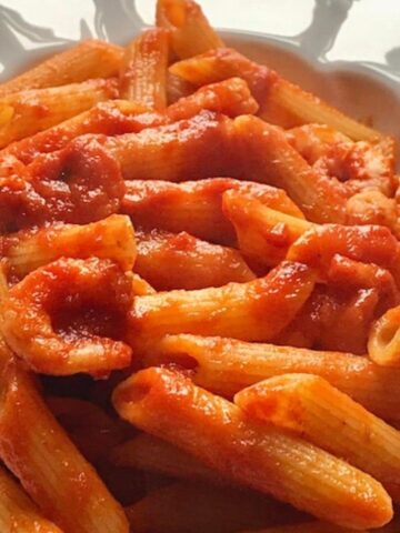 Pasta with shrimps in tomato sauce in a white bowl.