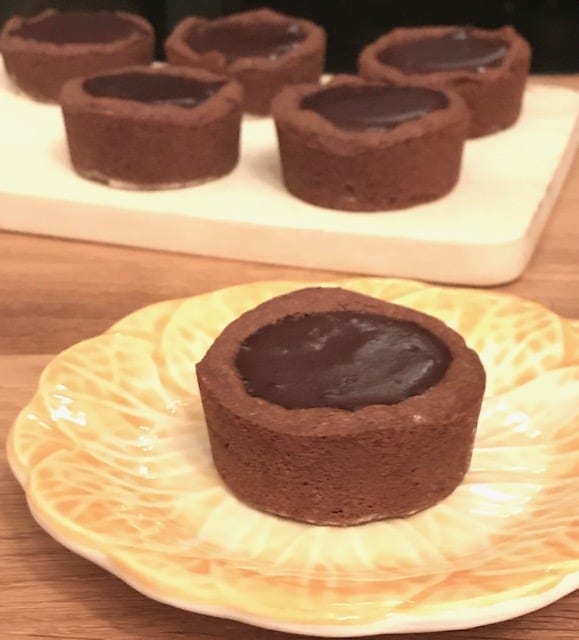 chocolate filled cookie cup on yellow plate with more cookie cups in the background