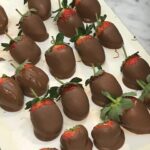 large stawberries dipped in chocolate on parchment paper