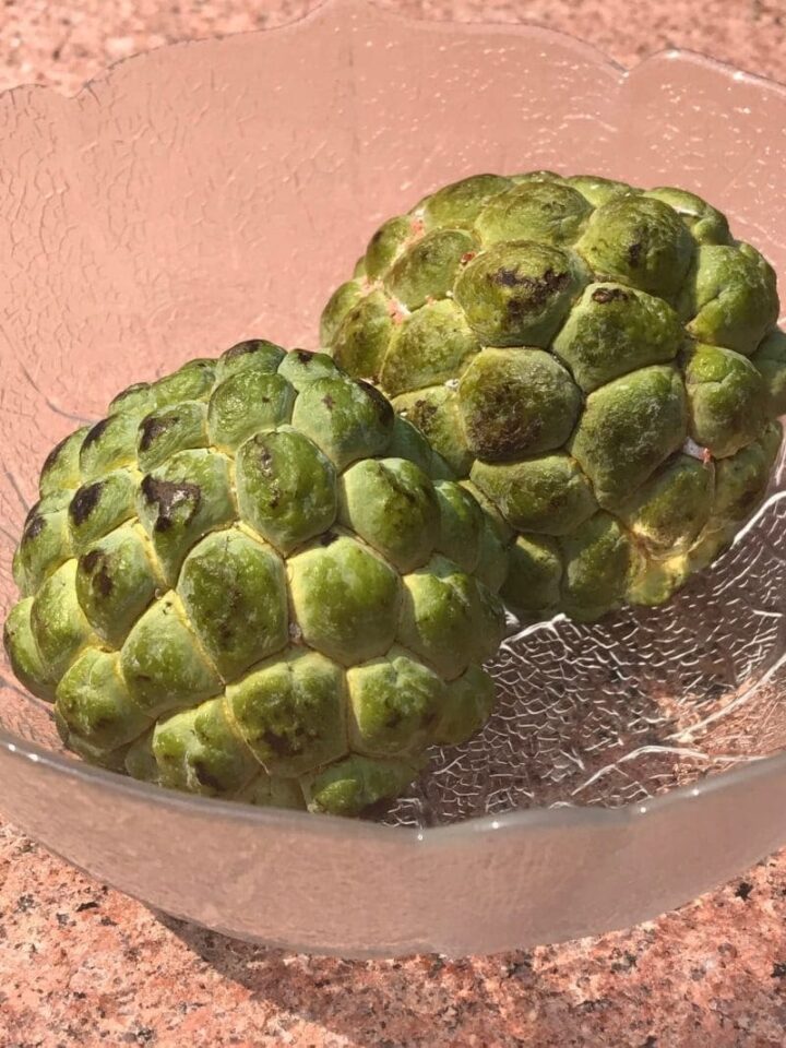 two custard apples in a glass bowl