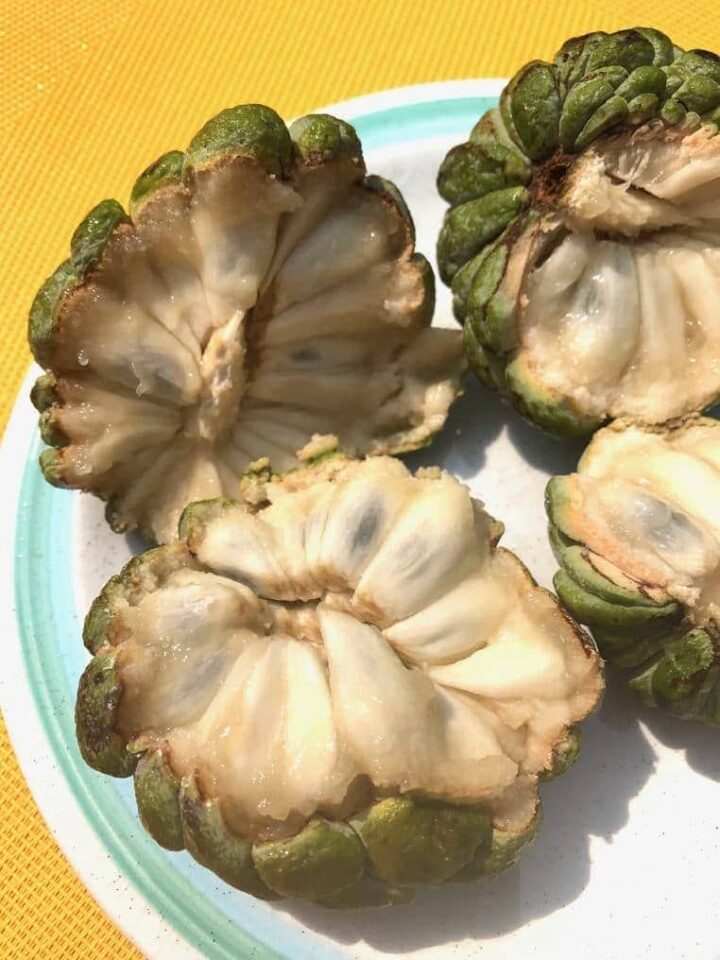 two custard apples cut in half showing inside flesh and seeds