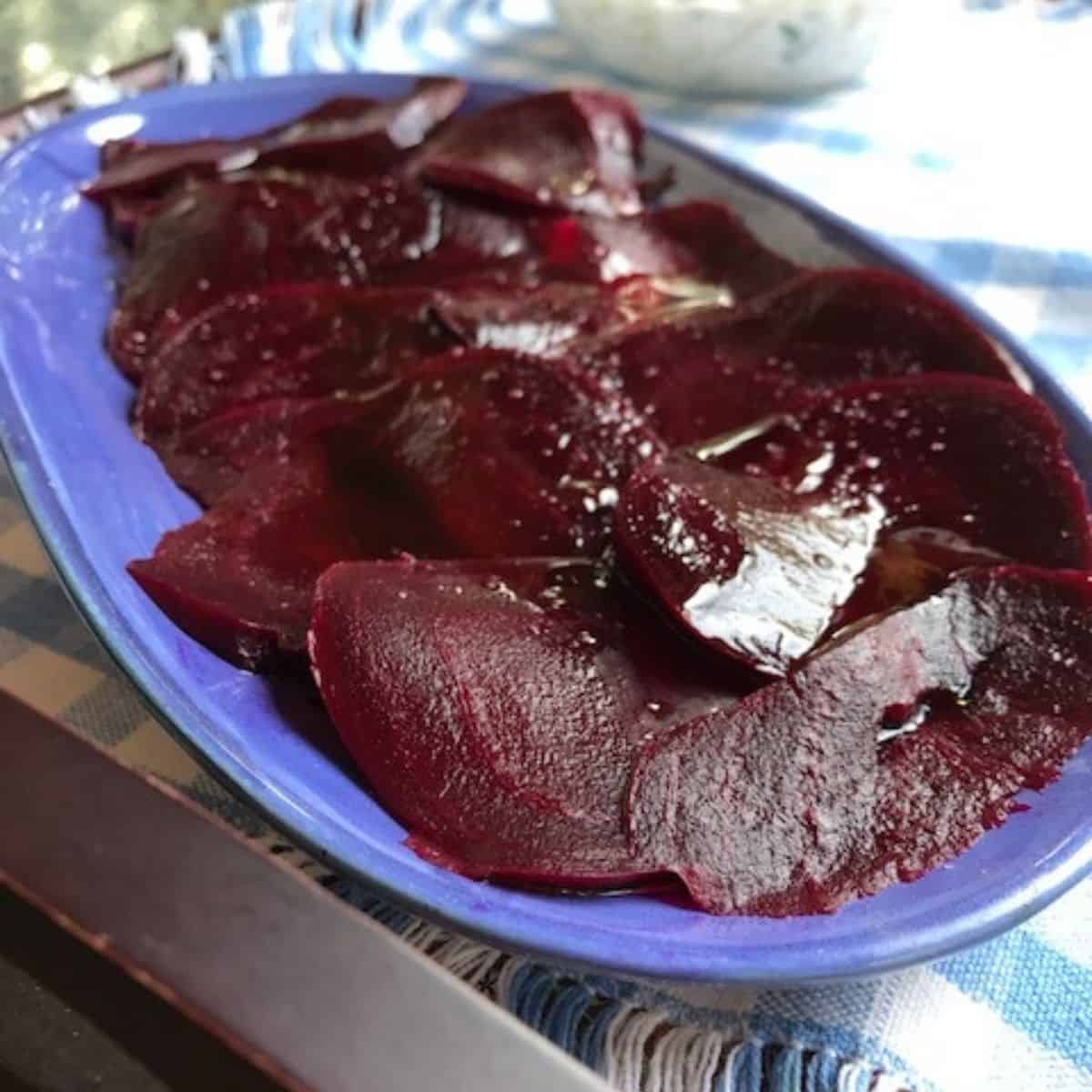 Sliced boiled beets on a blue dish.