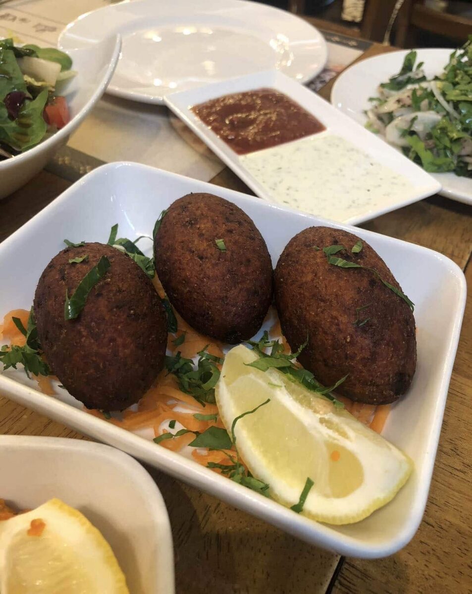 close up of 3 icli kebabs with wedge of lemon