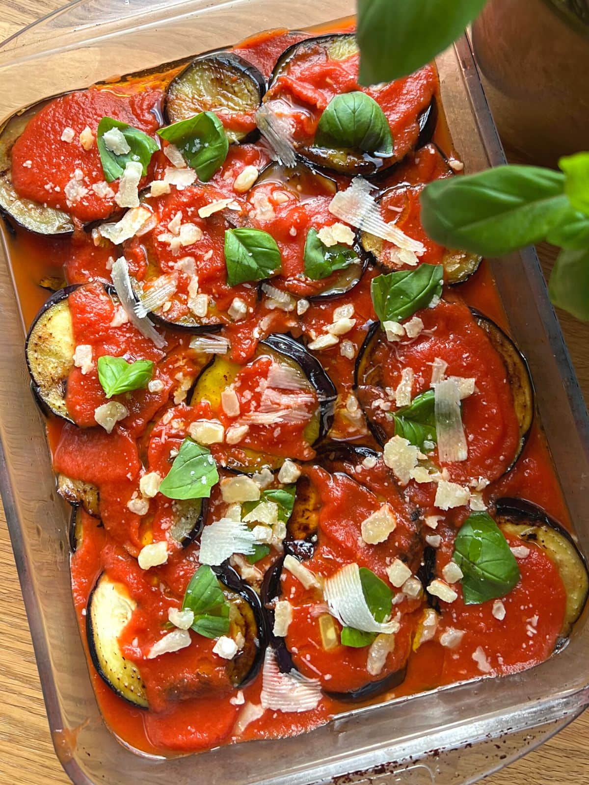 Eggplant parmesan in a dish with basil ready for baking.