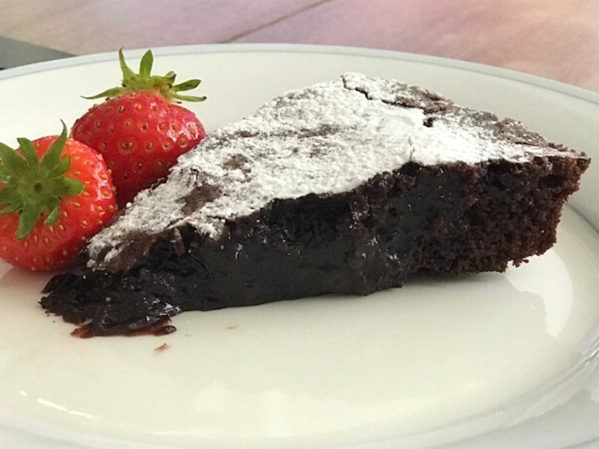 Image of slice of molten chocolate cake showing gooey texture with strawberries.