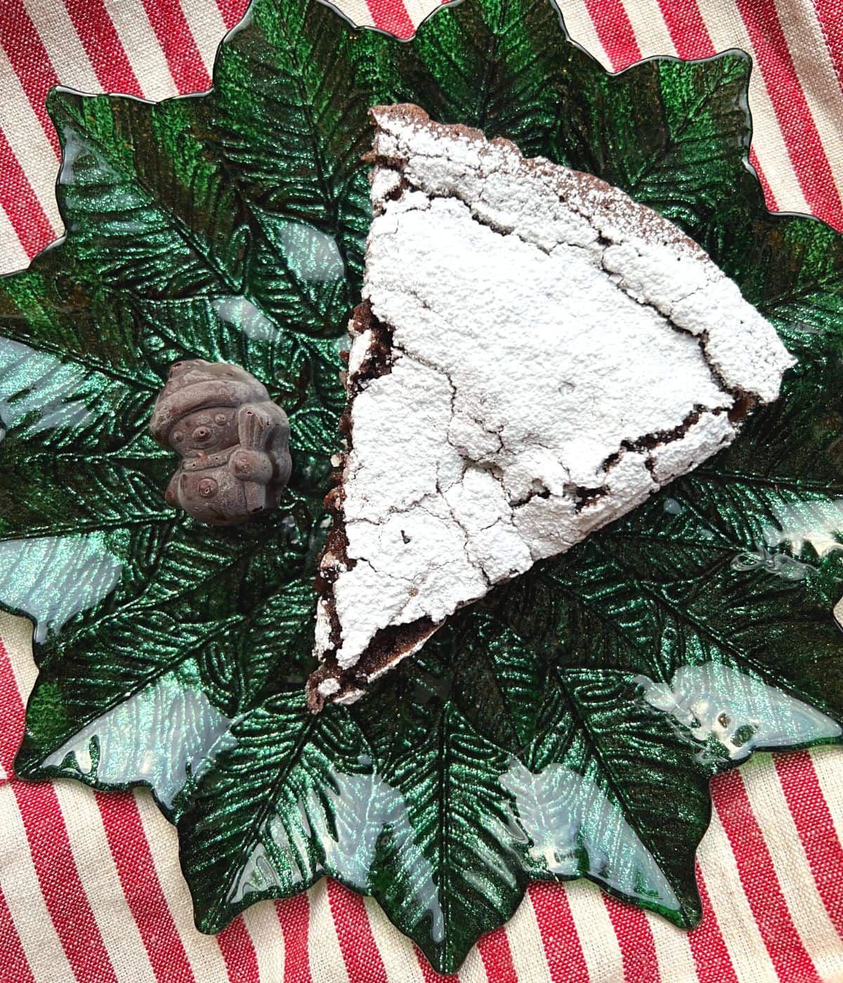 Slice of kladdkaka with powdered sugar on green plate.