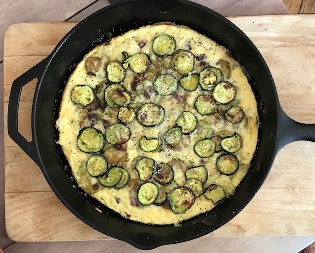 zucchini frittata in iron skillet on wooden board