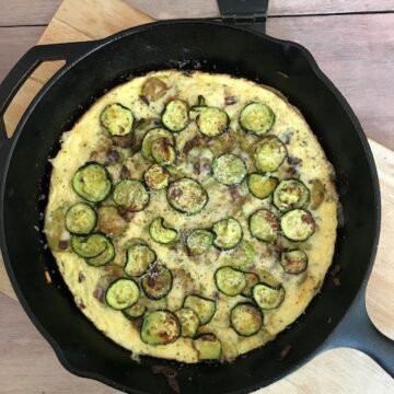 frittata in a skillet on a wodden board