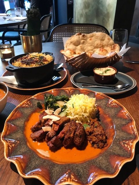 lamb rump, biryani, raita and naan on table