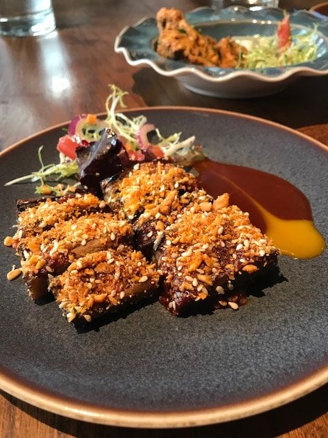 Pink aubergine covered with crushed peanuts