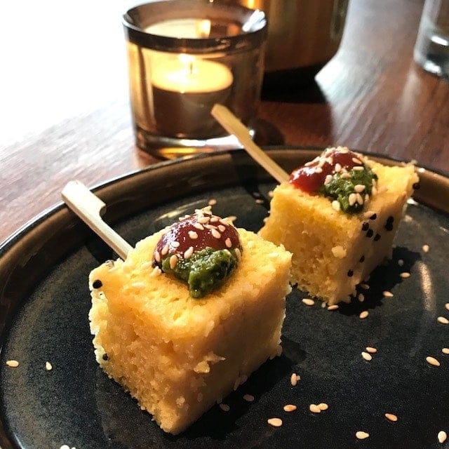 2 rectangles of yellow dhokla with chutney on top