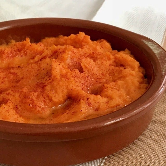 close up of hummus in a shallow terracotta bowl