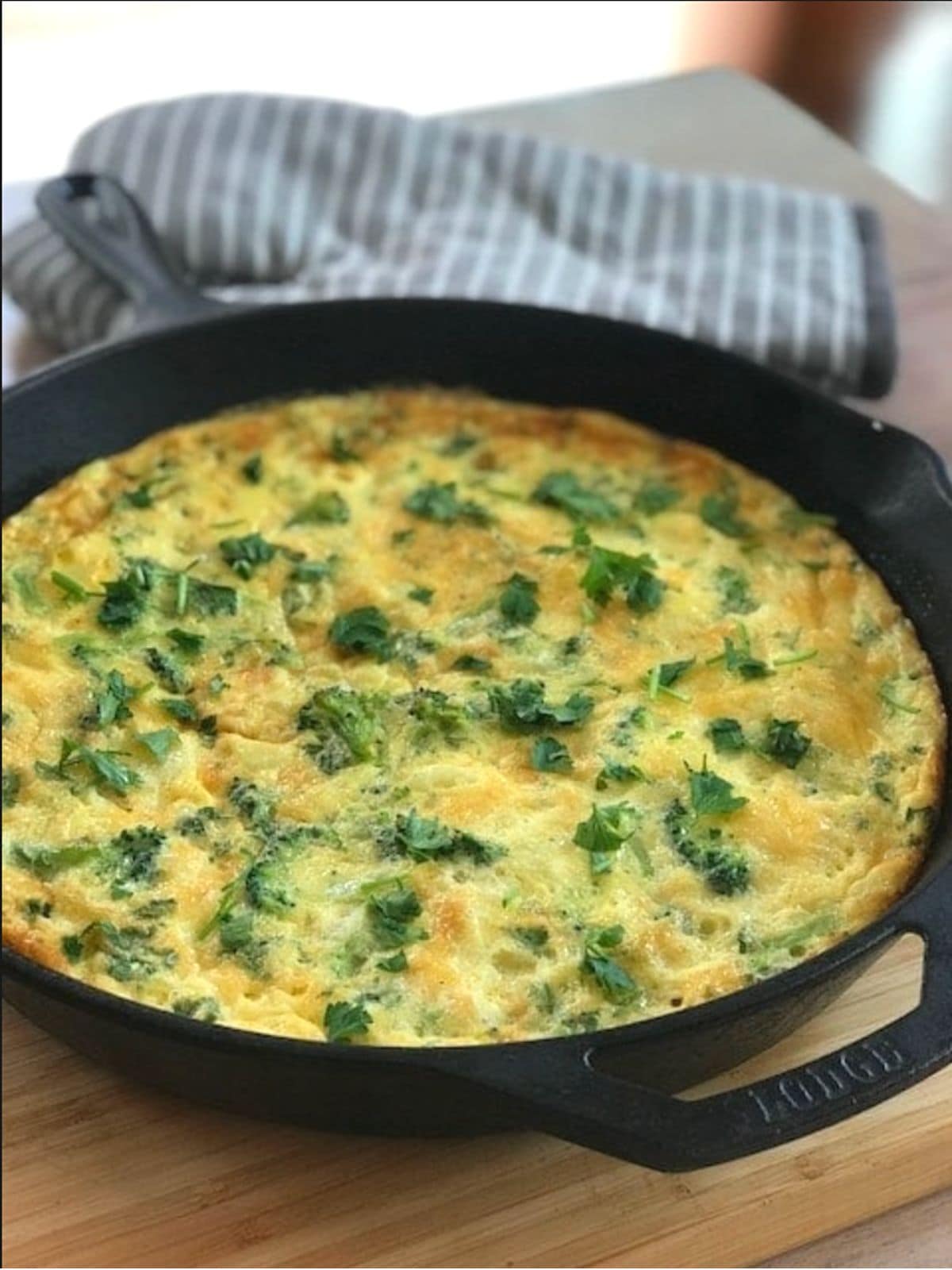 Broccoli potato frittata in a skillet next to oven glove.