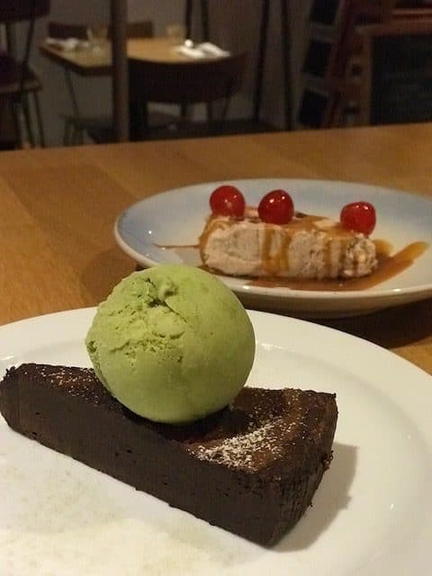 plate of chocolate cake with matcha ice cream and plate of Christmas parfait with cherries 