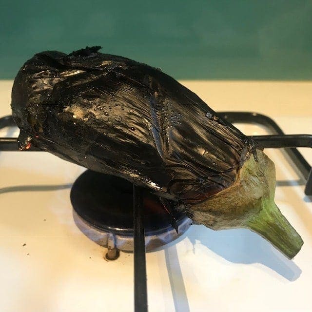 Eggplant roasting on the open fire on a hob