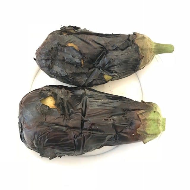 Two roasted eggplants on a white plate.