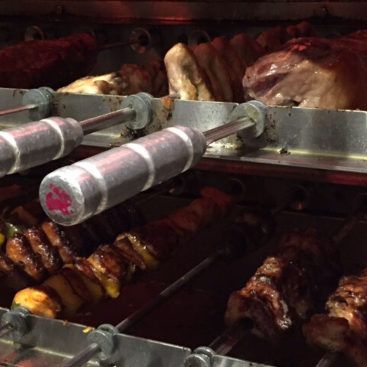 Skewers of meat cooking under a grill.