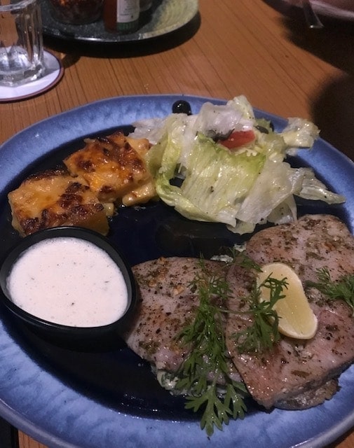 Grilled kingfish steak on a blue plate with salad