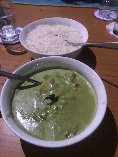 white bowl of thai green curry and another of plain boiled rice