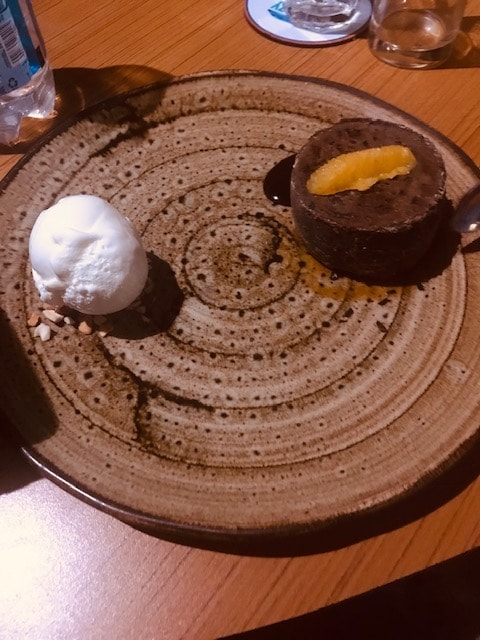 chocolate cake with vanilla ice cream on a brown plate