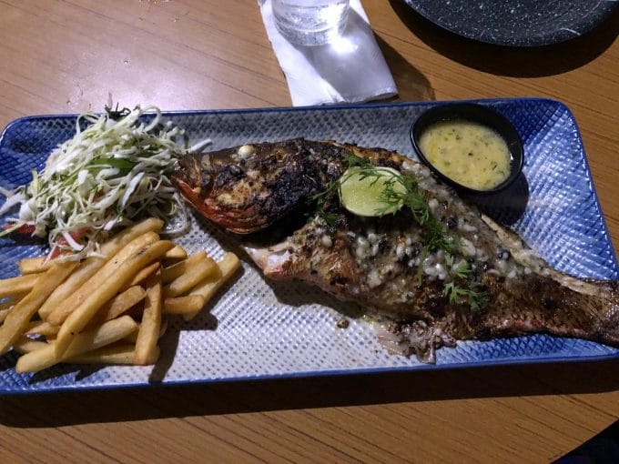 blue platter with a whole grilled seabass, salad and fries
