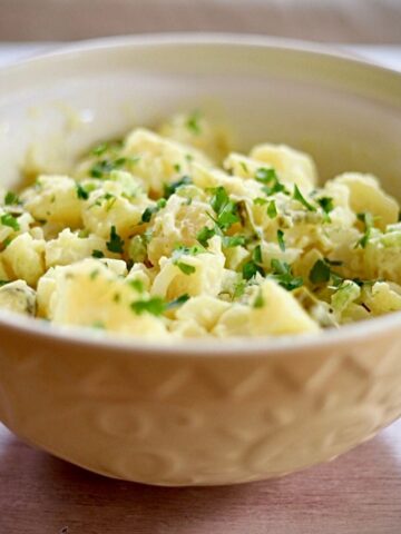 Image of potato salad with chopped parsley in large yellow bowl.