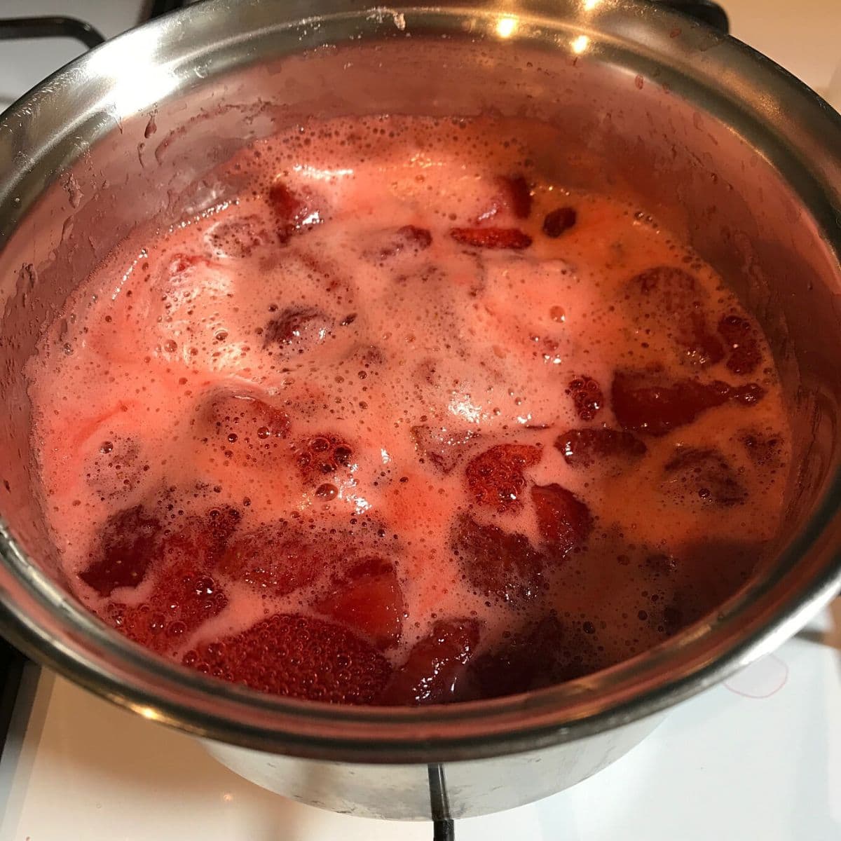 Strawberries boiling in small pan.