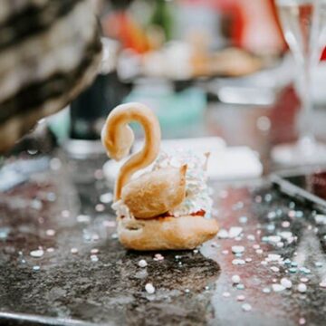 Single undecorated choux pastry swan on counter