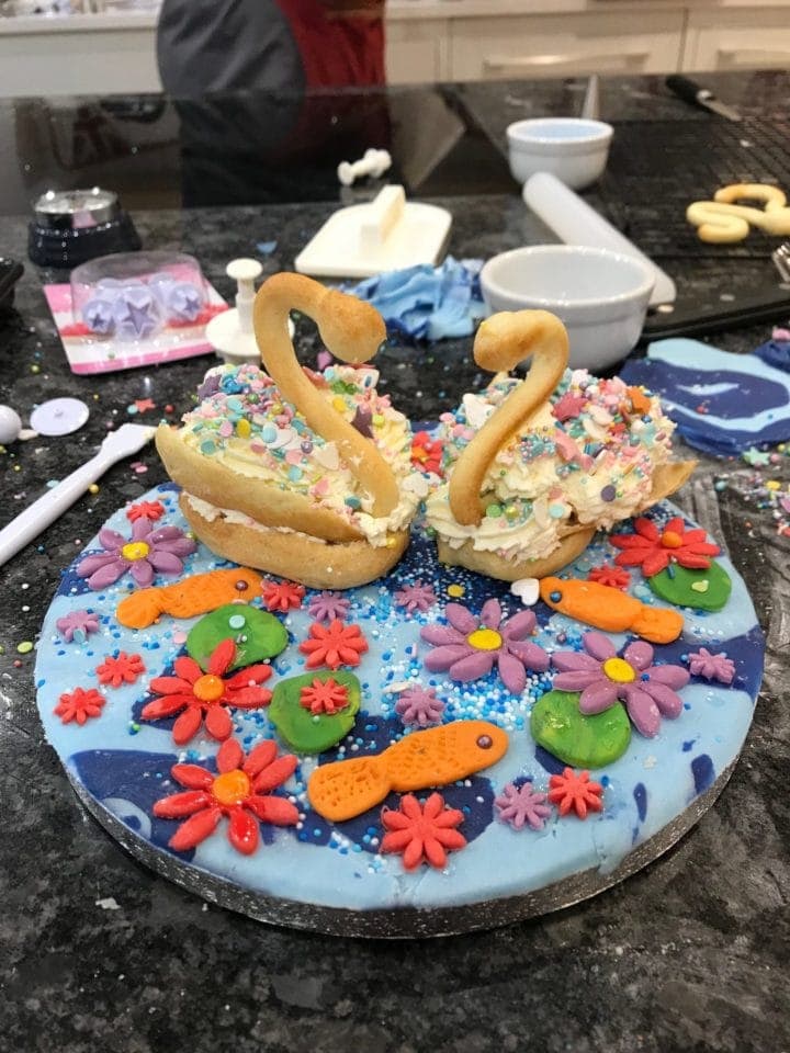 two decorated choux pastry swans on round board